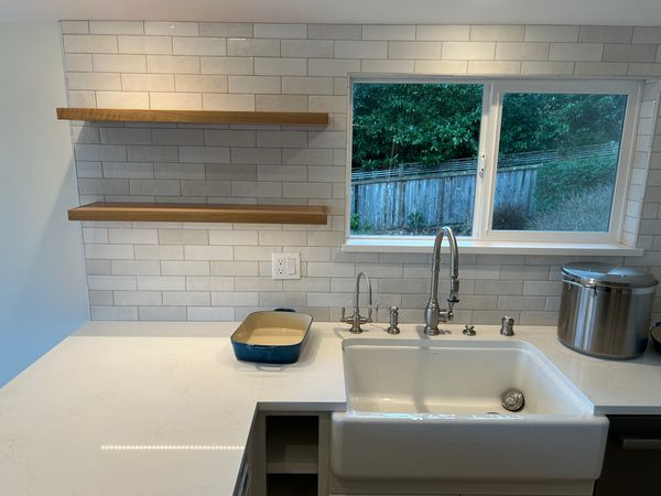 Kitchen with white subway tile, farmhouse sink and floating wood shelves