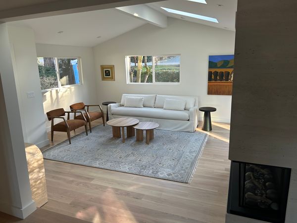 Remodeled living room with vaulted ceiling, skylights, light wood floors and fireplace