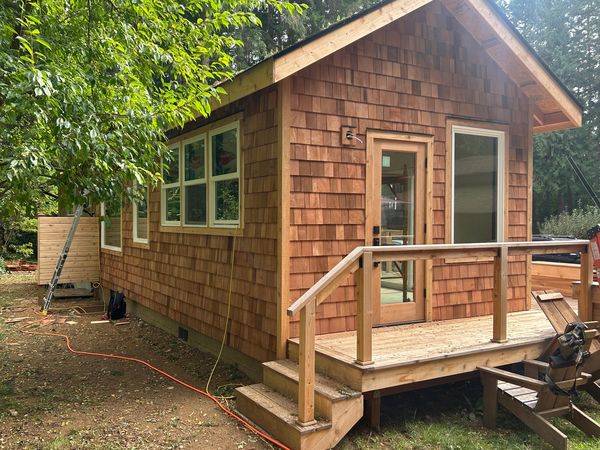 Small cottage with cedar shingle siding and a cedar deck with railing